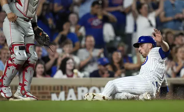 Chicago Cubs' Michael Busch slides into home to score on a single from Cody Bellinger during the seventh inning of a baseball game against the Philadelphia Phillies, Wednesday, July 3, 2024, in Chicago. (AP Photo/Erin Hooley)