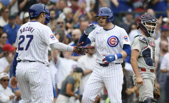 Chicago Cubs' Ian Happ, second from right, celebrates with teammates Seiya Suzuki (27) and Cody Bellinger, back left, at home plate after hitting a three-run home run during the fourth inning of a baseball game against the Philadelphia Phillies, Thursday, July 4, 2024, in Chicago. (AP Photo/Paul Beaty)