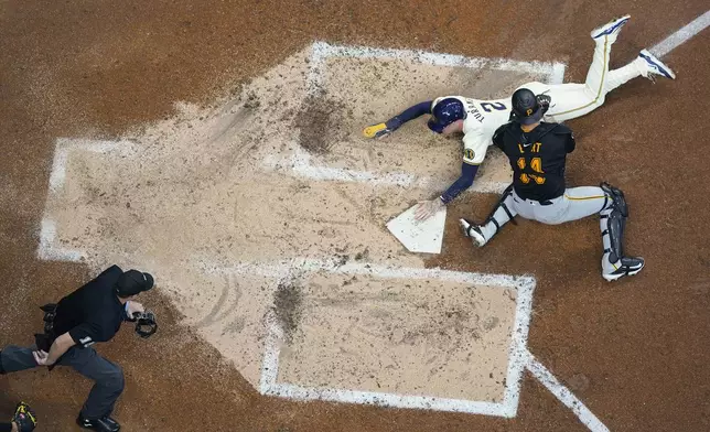 Milwaukee Brewers' Brice Turang (2) slides safely into home plate past the tag of Pittsburgh Pirates' Joey Bart to score a run on a double hit by Brewers' William Contreras during the fourth inning of a baseball game Wednesday, July 10, 2024, in Milwaukee. (AP Photo/Aaron Gash)