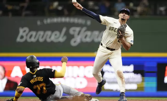 Milwaukee Brewers' Willy Adames, right, throws to first base to turn a double play after tagging Pittsburgh Pirates' Joshua Palacios (77) out at second base during the seventh inning of a baseball game Wednesday, July 10, 2024, in Milwaukee. (AP Photo/Aaron Gash)
