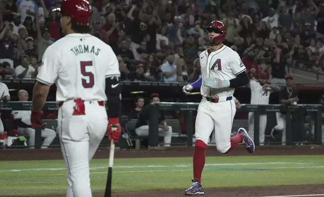 Arizona Diamondbacks' Lourdes Gurriel Jr., right, scores on a wild pitch in the sixth inning during a baseball game against the Pittsburgh Pirates, Friday, July 26, 2024, in Phoenix. (AP Photo/Rick Scuteri)