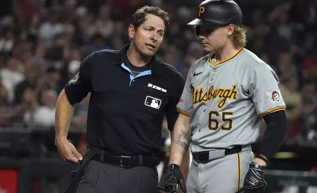 Pittsburgh Pirates' Jack Suwinski (65) talks to umpire Ben May, left, after striking out in the seventh inning during a baseball game against the Arizona Diamondbacks, Friday, July 26, 2024, in Phoenix. (AP Photo/Rick Scuteri)