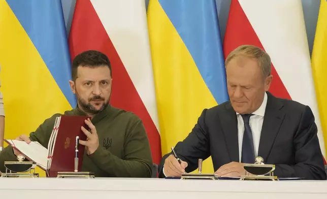 Poland's Prime Minister Donald Tusk, right, and Ukraine's President Volodymyr Zelenskyy sign an agreement of cooperation and defense, in Warsaw, Poland, on Monday, July 8, 2024. (AP Photo/Czarek Sokolowski)