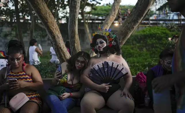 Revelers sit on a bench during a Pride parade marking the culmination of LGBTQ+ Pride month, in Panama City, Saturday, June 29, 2024. (AP Photo/Matias Delacroix)