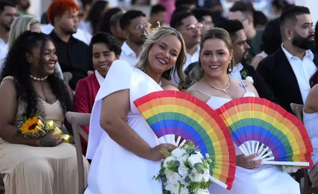Hellen Graciela and Leidiane Alves pose for a photo as they wait to be joined in matrimony at a same-sex mass wedding ceremony organized to mark Pride Month in Goiania, Brazil, Friday, June 28, 2024. (AP Photo/Eraldo Peres)