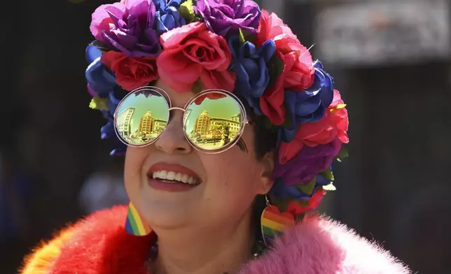 A reveler smiles as buildings are reflected in their face during a Pride Parade, Sunday, June 30, 2024, in San Francisco. (AP Photo/Ethan Swope)