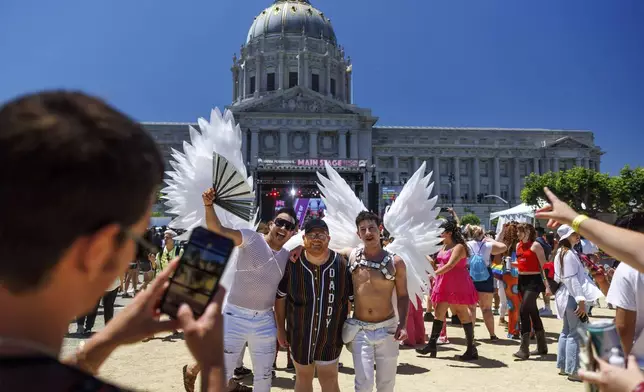 Revelers pose for photos with participants dressed in wings in front of San Francisco City Hall during a Pride Parade, Sunday, June 30, 2024, in San Francisco. (AP Photo/Ethan Swope)