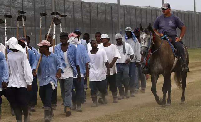 In this Aug. 18, 2011 photo, prison guards ride horses that were broken by inmates as they return from farm work detail at the Louisiana State Penitentiary in Angola, La. In September, several incarcerated workers along with the New Orleans-based advocacy group Voice of the Experienced filed a class-action lawsuit calling for an end to the farm line, and accusing the state of cruel and unusual punishment. But as temperatures soared in May, the men asked the court in an emergency filing to stop work during extreme heat. (AP Photo/Gerald Herbert)