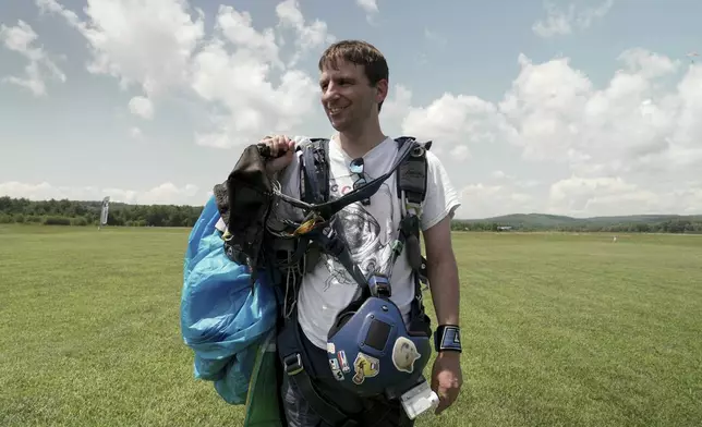 Casey Tylek, a U.S. Army veteran, carries equipment for skydiving in Orange, Mass. on July 13, 2024. (AP Photo/Shelby Lum)