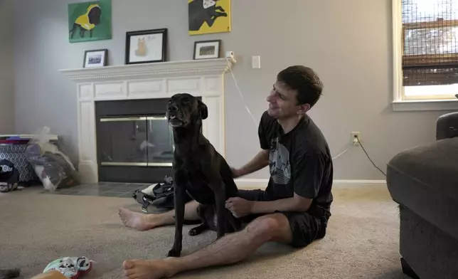 Casey Tylek, a U.S. Army veteran, sits with his dog, Cider, at his home in Leominster, Mass., on July 13, 2024. (AP Photo/Shelby Lum)