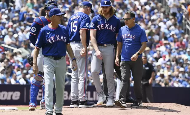 Texas Rangers starting pitcher Jon Gray, center right, exits with an undisclosed injury before throwing a single pitch against the Toronto Blue Jays in first-inning baseball game action in Toronto, Sunday, July 28, 2024. (Jon Blacker/The Canadian Press via AP)