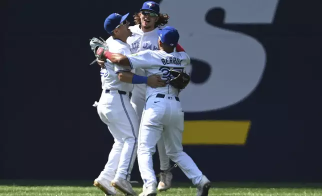 From left to right, Toronto Blue Jays Daulton Varsho, Addison Barger and Stewart Berroa celebrate after their victory over the Texas Rangers in a baseball game in Toronto, Sunday, July 28, 2024. (Jon Blacker/The Canadian Press via AP)