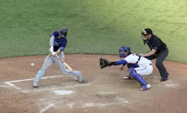 Tampa Bay Rays' Brandon Lowe, left, hits an RBI single as Toronto Blue Jays catcher Danny Jansen, center, looks on during seventh-inning baseball game action in Toronto, Thursday, July 25, 2024. (Chris Young/The Canadian Press via AP)