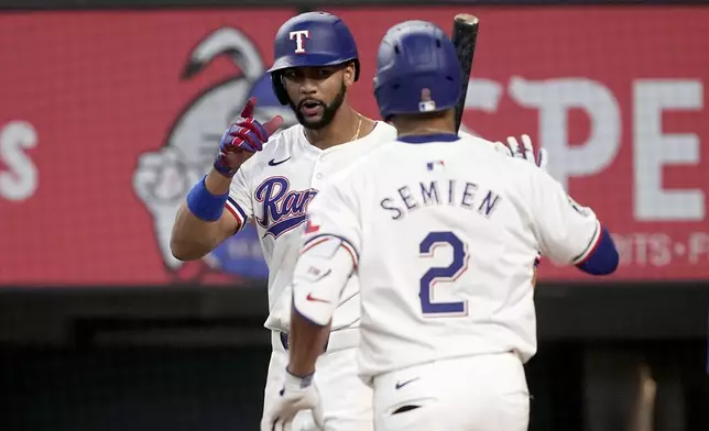 Texas Rangers' Leody Taveras, left, and Marcus Semien (2) celebrate after Semien hit a two-run home run that also scored Taveras against the Tampa Bay Rays in the seventh inning of a baseball game in Arlington, Texas, Saturday, July 6, 2024. (AP Photo/Tony Gutierrez)