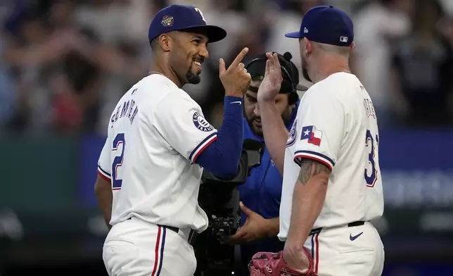 Texas Rangers' Marcus Semien, left, and Kirby Yates, right, celebrate after their win over the Tampa Bay Rays in a baseball game in Arlington, Texas, Saturday, July 6, 2024. (AP Photo/Tony Gutierrez)