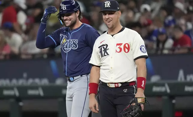 Texas Rangers first baseman Nathaniel Lowe (30) and his brother Tampa Bay Rays' Josh Lowe, left, laugh at first base after Josh singled during the sixth inning of a baseball game in Arlington, Texas, Friday, July 5, 2024. (AP Photo/LM Otero)