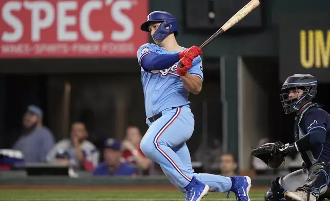 Texas Rangers' Wyatt Langford, left, follows through on a single as Tampa Bay Rays catcher Ben Rortvedt, right, looks on in the eighth inning of a baseball game in Arlington, Texas, Sunday, July 7, 2024. (AP Photo/Tony Gutierrez)