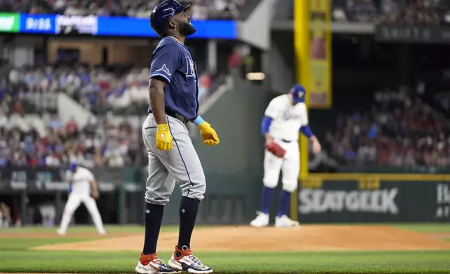 Tampa Bay Rays' Randy Arozarena, foreground, walks to first after being hit by a pitch from Texas Rangers starter Andrew Heaney, back right, in the first inning of a baseball game in Arlington, Texas, Saturday, July 6, 2024. (AP Photo/Tony Gutierrez)