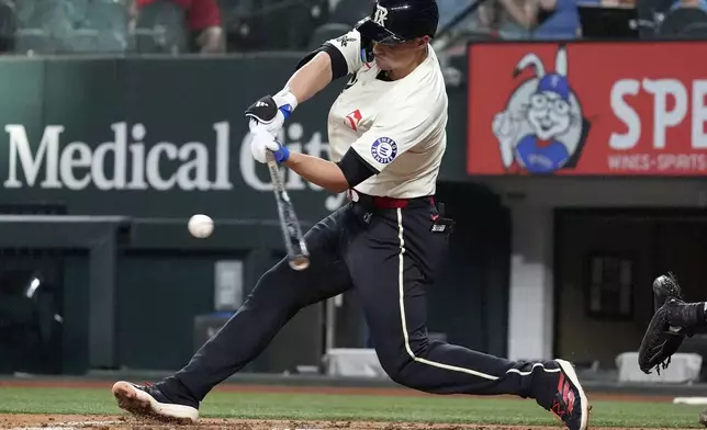 Texas Rangers' Corey Seager hits a double that scored teammates Jonathan Ornelas and Marcus Semien during the third inning of a baseball game against the Tampa Bay Rays in Arlington, Texas, Friday, July 5, 2024. (AP Photo/LM Otero)