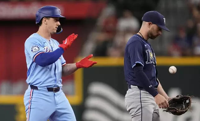 Texas Rangers' Wyatt Langford, left, stands on second base behind Tampa Bay Rays' Brandon Lowe, right, after hitting a run-scoring double in the first inning of a baseball game in Arlington, Texas, Sunday, July 7, 2024. Rangers' Corey Seager scored on the hit. (AP Photo/Tony Gutierrez)