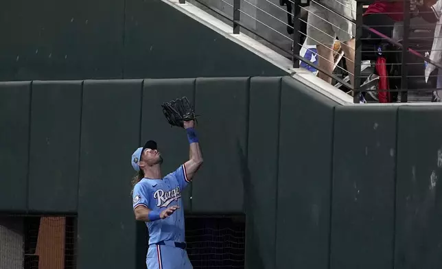 Texas Rangers right fielder Travis Jankowski, bottom, tries to catch a fly ball hit by Tampa Bay Rays' Randy Arozarena that a fan, top, catches in the seventh inning of a baseball game in Arlington, Texas, Sunday, July 7, 2024. Arozarena was called out on fan interference. (AP Photo/Tony Gutierrez)