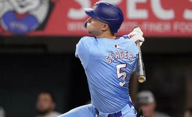 Texas Rangers' Corey Seager follows through on a three-run home run against the Tampa Bay Rays in the fourth inning of a baseball game in Arlington, Texas, Sunday, July 7, 2024. Rangers' Travis Jankowski and Marcus Semien also scored on the hit. (AP Photo/Tony Gutierrez)