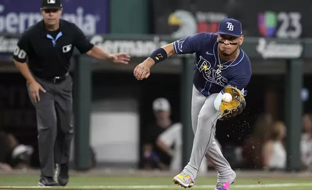 Tampa Bay Rays third baseman Isaac Paredes, right, reaches out to field a ground ball hit byTexas Rangers' Adolis Garcia in the second inning of a baseball game in Arlington, Texas, Saturday, July 6, 2024. Garcia was out at first on the play. (AP Photo/Tony Gutierrez)