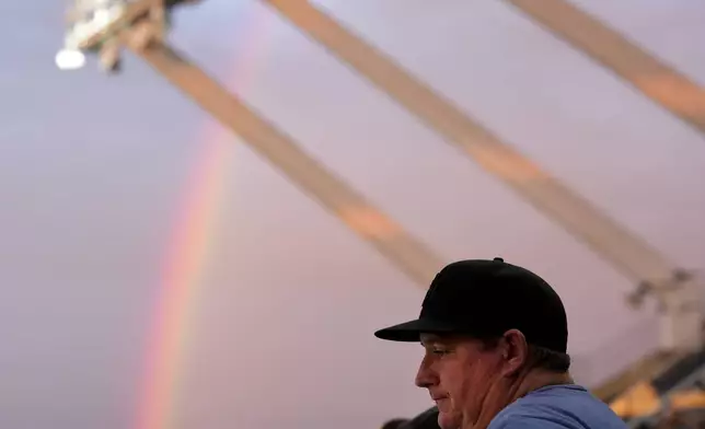 A fan watches a rainbow from the upper deck during the fifth inning of a baseball game between the Kansas City Royals and the Tampa Bay Rays Wednesday, July 3, 2024, in Kansas City, Mo. (AP Photo/Charlie Riedel)