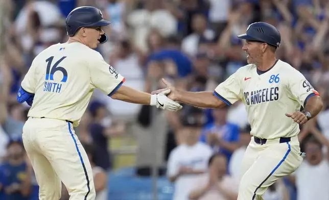 Los Angeles Dodgers' Will Smith, left, celebrates with first base coach Clayton McCullough, right, after driving in the winning run with a single during the 11th inning of a baseball game against the Boston Red Sox, Saturday, July 20, 2024, in Los Angeles. (AP Photo/Marcio Jose Sanchez)