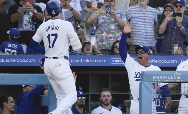 Los Angeles Dodgers designated hitter Shohei Ohtani, left, is greeted by manager Dave Roberts, right, after his solo home run during the fifth inning of a baseball game against the Boston Red Sox, Sunday, July 21, 2024, in Los Angeles. (AP Photo/Ryan Sun)