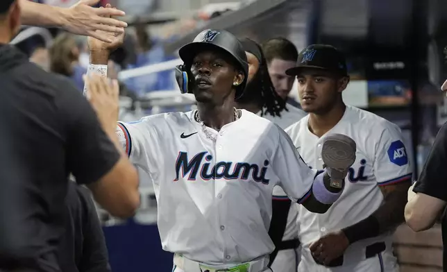 Miami Marlins' Jazz Chisholm Jr. is congratulated by the team after scoring during the first inning of a baseball game against the Boston Red Sox, Wednesday, July 3, 2024, in Miami. (AP Photo/Marta Lavandier)