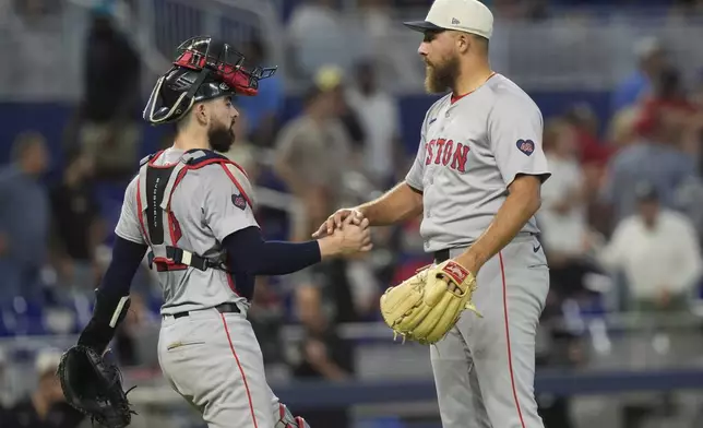 Boston Red Sox relief pitcher Greg Weissert, right, and catcher Reese McGuire, left, shake hands at the end of a baseball game against the Miami Marlins, Thursday, July 4, 2024, in Miami. (AP Photo/Marta Lavandier)