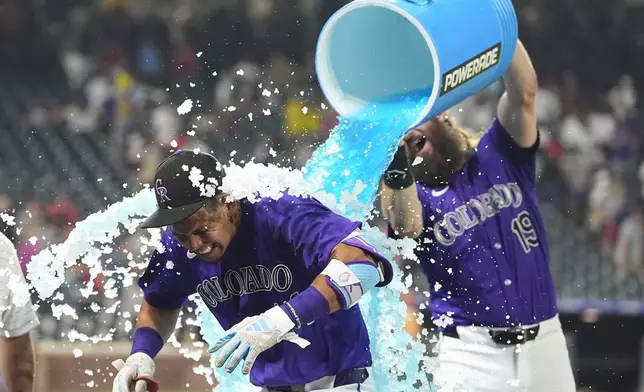 Colorado Rockies' Charlie Blackmon, back, douses Ezequiel Tovar after his walkoff RBI single off Boston Red Sox relief pitcher Chase Anderson in the 12th inning of a baseball game Monday, July 22, 2024, in Denver. (AP Photo/David Zalubowski)