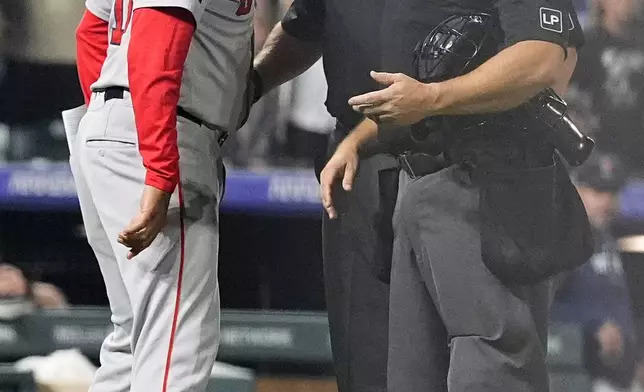 Boston Red Sox manager Alex Cora, left, argues with home plate umpire Mark Wegner, front right, and third base umpire Bruce Dreckman in the 11th inning of a baseball game against the Colorado Rockies, Monday, July 22, 2024, in Denver. (AP Photo/David Zalubowski)