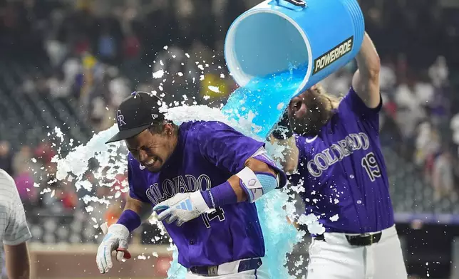 Colorado Rockies' Charlie Blackmon, back, douses Ezequiel Tovar after his walkoff RBI single off Boston Red Sox relief pitcher Chase Anderson in the 12th inning of a baseball game Monday, July 22, 2024, in Denver. (AP Photo/David Zalubowski)