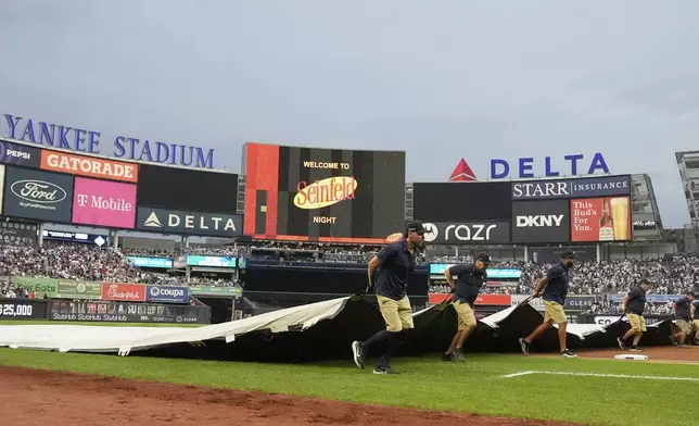 Members of the grounds crew cover the field at Yankee Stadium during a rain delay during the third inning of a baseball game between the New York Yankees and the Boston Red Sox, Friday, July 5, 2024, in New York. (AP Photo/Frank Franklin II)