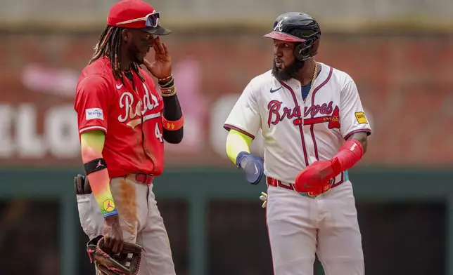 Cincinnati Reds shortstop Elly De La Cruz, left, discusses the last play with Atlanta Braves' Marcell Ozuna, right, in the first inning of the first baseball game, Wednesday, July 24, 2024, in Atlanta. (AP Photo/Jason Allen)