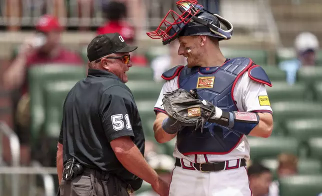 Umpire Marvin Hudson, left, chats with Atlanta Braves catcher Sean Murphy, right, in the sixth inning of the first baseball game of a doubleheader against the Cincinnati Reds, Wednesday, July 24, 2024, in Atlanta. (AP Photo/Jason Allen)