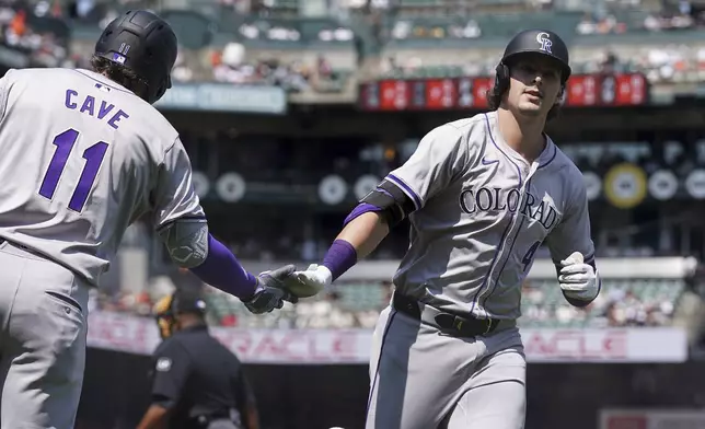 Colorado Rockies' Michael Toglia (4) celebrates with Jake Cave (11) after hitting a solo home run againsr the San Francisco Giants in the seventh inning of a baseball game in San Francisco, Sunday, July 28, 2024. (AP Photo/Kavin Mistry)