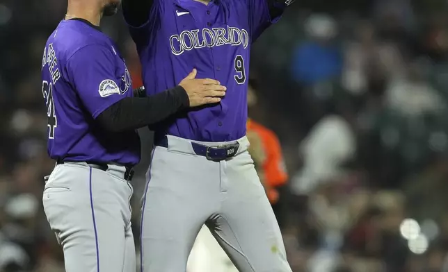 Colorado Rockies' Brenton Doyle, right, celebrates next to third base coach Warren Schaeffer after hitting a two-run triple against the San Francisco Giants during the eighth inning of a baseball game Friday, July 26, 2024, in San Francisco. (AP Photo/Godofredo A. Vásquez)