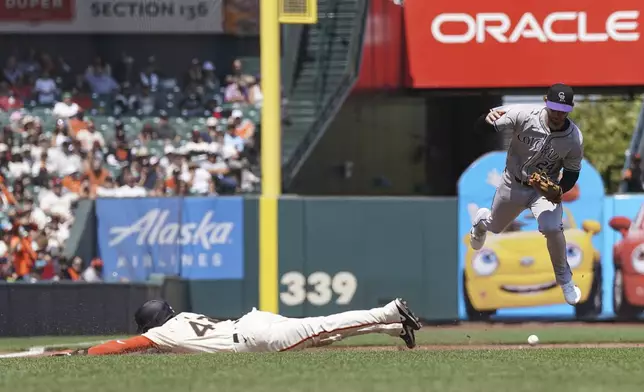 Colorado Rockies third baseman Ryan McMahon, right, drops the ball attempting to tag out San Francisco Giants' Derek Hill during the sixth inning of a baseball game in San Francisco, Sunday, July 28, 2024. (AP Photo/Kavin Mistry)