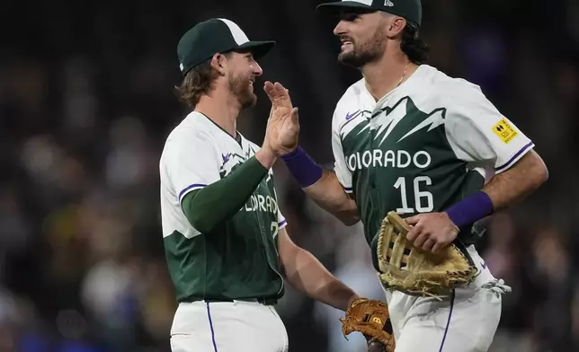 Colorado Rockies third baseman Ryan McMahon, left, is congratulated by center fielder Sam Hilliard after defeating the Kansas City Royals in a baseball game Saturday, July 6, 2024, in Denver. (AP Photo/David Zalubowski)