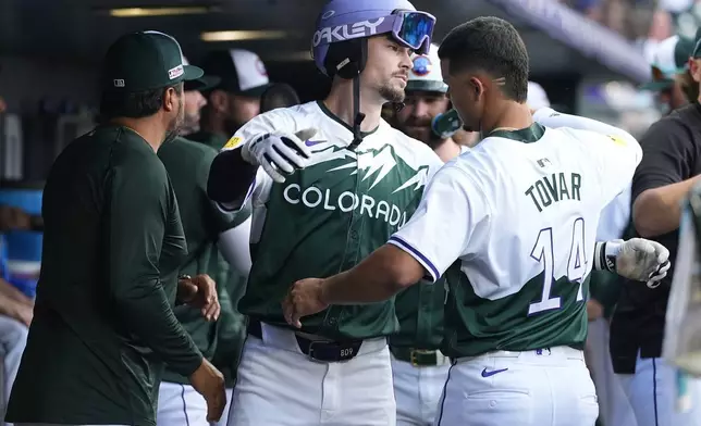 Colorado Rockies' Brenton Doyle, center, hugs Ezequiel Tovar as Vinny Castilla, special assistant to the general manager, looks on as Doyle returns to the dugout after hitting a teo-run home run off Kansas City Royals starting pitcher Seth Lugo in the second inning of a baseball game Saturday, July 6, 2024, in Denver. (AP Photo/David Zalubowski)