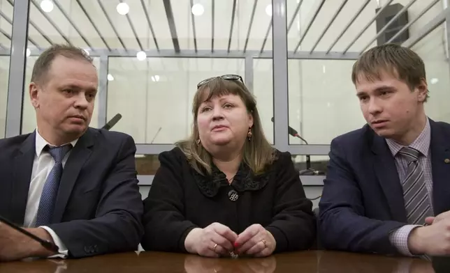 FILE - Oksana Sevastidi with her lawyers Evgeny Smirnov, right, and Ivan Pavlov, awaits a court hearing in Moscow, Russia, Wednesday, March 15, 2017. Sevastidi, a bakery worker in the Black Sea resort of Sochi, was convicted of treason and sentenced to seven years in prison after she sent a text message to a friend in neighboring Georgia about seeing military equipment carried on a nearby railway prior to Russia’s brief war in 2008 with its neighbor. President Vladimir Putin pardoned her in 2017. (AP Photo, File)