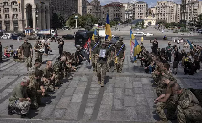 Ukrainian servicemen carry a portrait and coffin of British combat medic, volunteer, Peter Fouche, 49 who was killed on June 27 during his work in East Ukraine, at the funeral ceremony on the city's main square in Kyiv, Ukraine, Saturday, July 6, 2024. Peter was founder of a charity organization, which provides vehicles, drones and other needs to Ukrainian servicemen. (AP Photo/Alex Babenko)