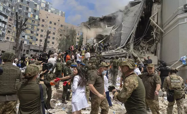 Rescuers, volunteers and medical workers clean up the rubble and search victims after Russian missile hit the country's main children hospital Okhmadit during massive missile attack on many Ukrainian cities in Kyiv, Ukraine, Monday, July 8, 2024. A major Russian missile attack across Ukraine killed at least 20 people and injured more than 50 on Monday, officials said, with one missile striking a large children’s hospital in the capital, Kyiv, where emergency crews searched rubble for casualties. (AP Photo/Efrem Lukatsky)