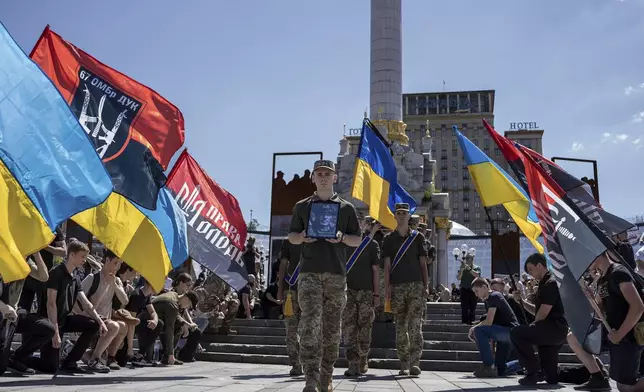 Ukrainian servicemen carry a portrait and coffin of British combat medic, volunteer, Peter Fouche, 49 who was killed on June 27 during his work in East Ukraine, at the funeral ceremony on the city's main square in Kyiv, Ukraine, Saturday, July 6, 2024. Peter was founder of a charity organization, which provides vehicles, drones and other needs to Ukrainian servicemen. (AP Photo/Alex Babenko)