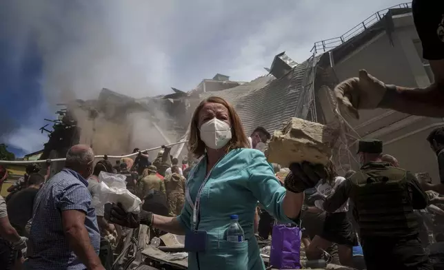 Emergency workers at the site of Okhmatdyt children’s hospital hit by Russian missiles, in Kyiv, Ukraine, Monday, July 8, 2024. Russian missiles have killed at least seven people and struck a children’s hospital in the Ukrainian capital, Kyiv, authorities say. (AP Photo/Evgeniy Maloletka)