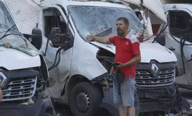A worker of Nova Poshta delivery gestures in front of destroyed trucks after a Russian attack on his office, in Kharkiv, Ukraine, Sunday, June 30, 2024. At least one person was killed and several injured. (AP Photo/Andrii Marienko)
