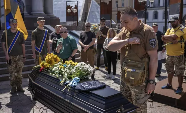 Comrade of British combat medic, volunteer, Peter Fouche, 49 who was killed on June 27 during his work in East Ukraine, says his last goodbye at the funeral ceremony on the city's main square in Kyiv, Ukraine, Saturday, July 6, 2024. Peter was founder of a charity organization, which provides vehicles, drones and other needs to Ukrainian servicemen. (AP Photo/Alex Babenko)